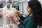 Dressmaker fixing white lace wedding dress on a mannequin in tailor studio