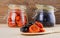 Dried apricots and prunes in a wooden spoon in the foreground and in glass jars in the background in defocus.