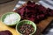 Dried beetroot with bowl of salt and black pepper on chopping board