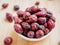 Dried berries of Dog Rose or Rosa canina. Dry fruits of sweet-brier or rose hips on white bowl on wooden background