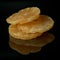 Dried candied pineapple rings on a black mirror surface with reflections isolated on black