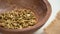 Dried cardamon seed pods falling into a kitchen wooden bowl with rough rustic sackcloth.