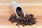 Dried cloves in wooden spice spoon and scattered beside closeup