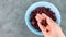 Dried cranberries blue bowl in hand top view. Healthy tasty dry red berries. Organic nutritious delicious farmers fruits snack