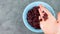 Dried cranberries blue bowl in hand top view. Healthy tasty dry red berries. Organic nutritious delicious farmers fruits snack