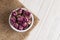 Dried damask rose buds in small bowl on white wooden table