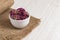 Dried damask rose buds in small white bowl on wooden table.