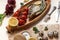 Dried fish with lemon, herbs, oil, vegetables and spices on wooden board.