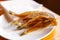 Dried fish strung on a wooden skewer lies on a plate