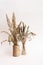 Dried flowers. Field dry spikelets and herbs in vases on a light pink background.