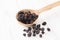Dried fruits of black currant in wooden spoon on white wooden table
