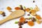 Dried fruits and nuts, apricot, almond, hazelnut pear prune and macadamia with bamboo wooden spoon on white background.