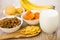 Dried fruits, spoon with corn flakes, bananas and glass milk