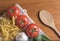 Dried fusilli pasta with tomatoes, basil, garlic and a wooden spoon