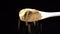 Dried ginger powder spice on a spoon is poured out isolated on a black background. Dry seasoning in spoon. Spices and