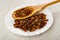 Dried grape in bamboo spoon, raisin in plate on wooden table