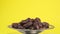 Dried large dates on a metal plate that rotates, yellow background, majul variety