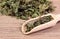 Dried nettle with spoon on wooden surface