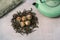 Dried Organic Black Tea Leaves and aromatic green tea flowers ball on gray Background. Composition with Iron teapot and