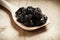 Dried plums prunes on wooden spoon