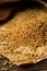 Dried, raw fenugreek seed on brown packing paper on rustic wooden table background