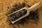 Dried, raw white tea leaves in wooden scoop over brown packing paper background top view flat lay from above