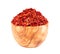 Dried red chili flakes in olive bowl, isolated on white background. Chopped chilli cayenne pepper. Spices and herbs.