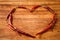 Dried red chili peppers in heart shape on rustic, dark wood cut