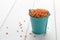 Dried red lentils in small blue bucket on white wooden background.