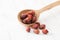 Dried rose hips in wooden spoon on white wooden table