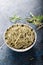 Dried rosemary in a bowl with fresh rosemary twigs