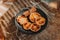 Dried slices of oranges, gingerbread cookies and cinnamon sticks on black plate