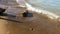 Drift peace of wood in sea waves near stones on sand beach