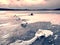 Drifting piece of iceberg and sun glaring on thick ice cover.