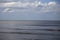 Driftwood Beach ocean view of calm waves, blue skies, and white wispy clouds.