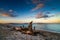 Driftwood on a sandy beach with turquoise ocean water and a colorful sunset sky