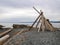 Driftwood Teepee tipi structure on a rock pebble beach by the water on the coastline