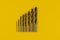 Drill bits of different sizes on yellow background,top view