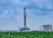 Drilling Rig and oil tanks with green cornfield in the foreground In South Texas Eagle Ford Shale