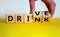 Drink or drive. Male hand flips a wooden cube and changes the inscription `drink` to `drive`. Beautiful yellow table, white