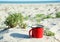 Drinking tea, coffee from a red metal cup on a wild sandy beach at the sea in summer