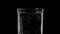 Drinking water in a glass on a black background. Mineral water with bubbles. Soda water