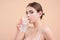 Drinking water. Young woman enjoy pure fresh mineral water, isolated on studio background. Thirsty woman hold glass aqua