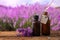 Dripping essential oil from pipette into bottle near lavender flowers on wooden table. Space for text