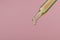 Dripping hydrophilic oil from pipette on pink background, closeup. Space for text