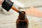 Dripping medical iodine from pipette into glass bottle, closeup