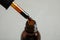 Dripping medical iodine from pipette into glass bottle on grey background, closeup