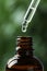 Dripping medical product from pipette into glass bottle against blurred background, closeup