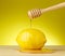 Dripping organic honey with lemon on yellow background
