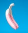 Dripping pink paint on white banana on blue background